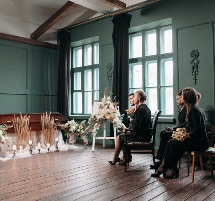 A peaceful indoor funeral ceremony scene with a pastor and seated mourners.