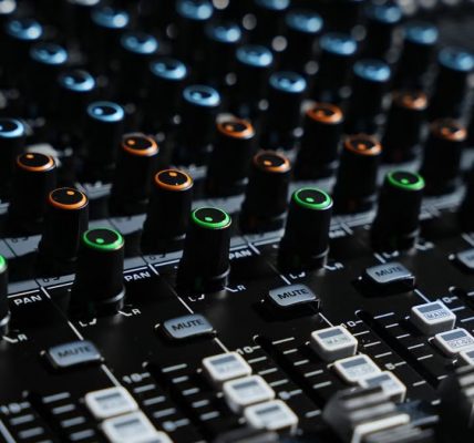 Detailed view of an audio mixing console with colorful lights in a professional studio setting.
