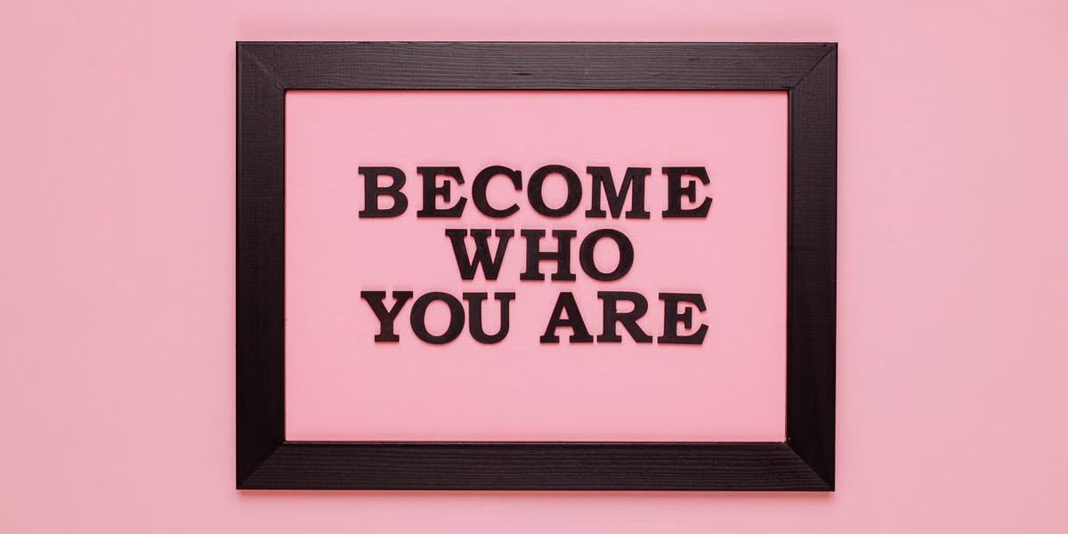 Inspiring quote 'Become Who You Are' framed on a vibrant pink wall, perfect for encouragement.