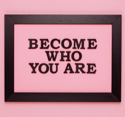 Inspiring quote 'Become Who You Are' framed on a vibrant pink wall, perfect for encouragement.